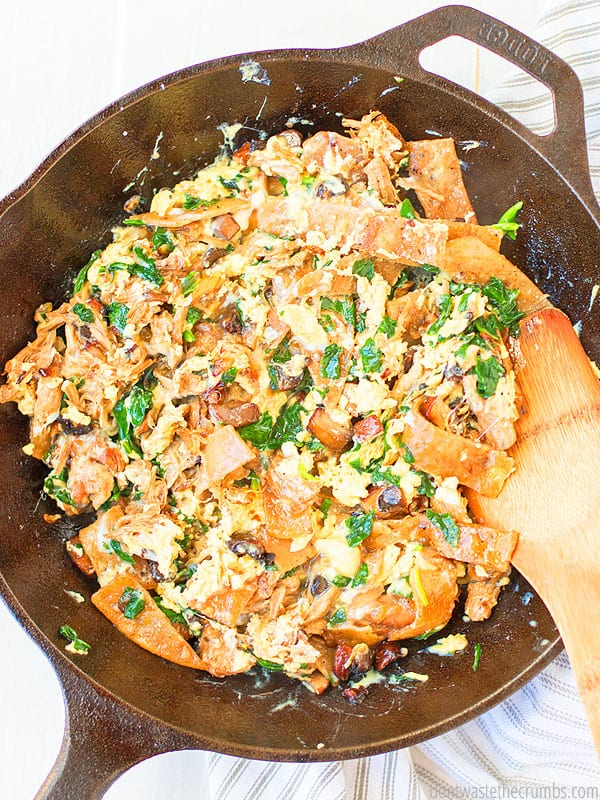 Cooked Migas with many ingredients mixed shown from above and being stirred with a wooden spoon. It looks absolutely mouth watering.