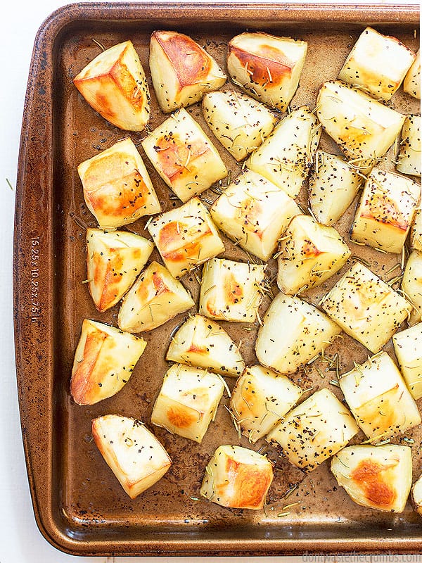 Sheet tray with roasted potatoes topped with herbs.