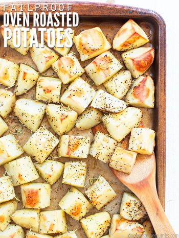 Sheet pan with roasted potatoes seasoned with herbs and a wooden spoon taking a scoop. Text overlay says, "Failproof Oven Roasted Potatoes".