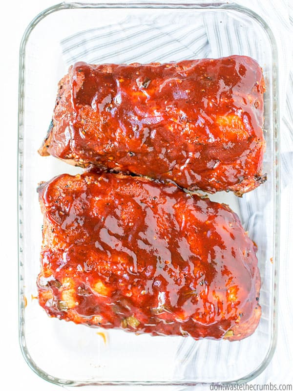 Two slabs of slow cooker ribs in a glass baking pan.