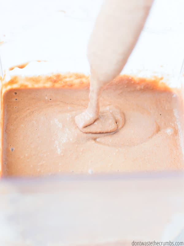 Batter for chocolate belgian waffles drips off of a spoon into the batter below.