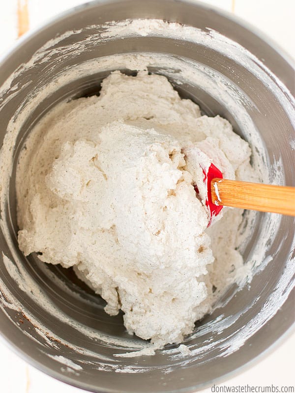 Stiffly whipped heavy cream in a bowl with a red silicone spatula that has a wooden handle. Get back to basics and avoid unnecessary chemicals with this simple homemade whipped cream!