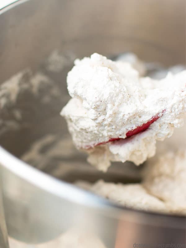 A scoop of delightful whipped cream from a metal bowl, on a silicone spatula. It is a versatile dessert topping that can be adjusted based on personal preferences!