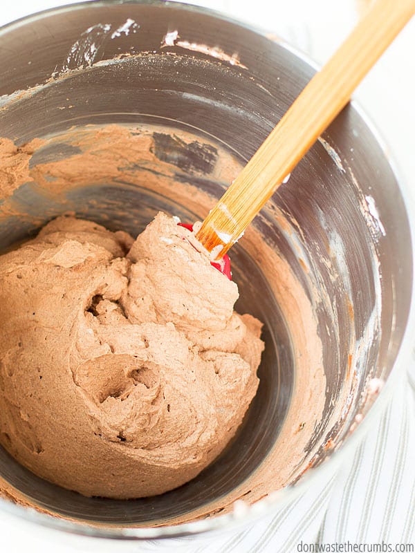 Mixing bowl of chocolate whipping cream and a spatula.