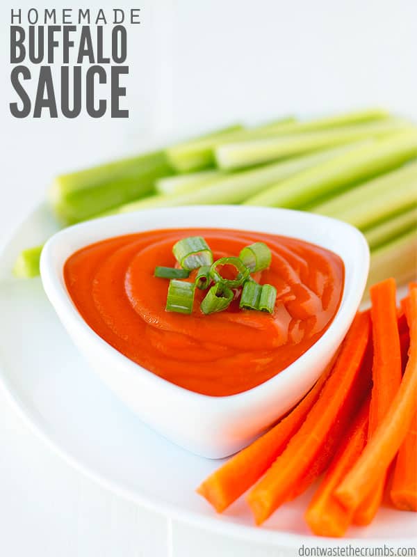 Image showing sliced celery sticks and sliced carrots sticks and a small triangle dish with homemade buffalo wing sauce (with chopped chives on top). Text overlay says Homemade Buffalo Sauce