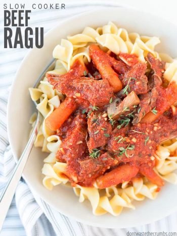Bowl of pasta topped with beef ragu, baby carrots and herbs. Text overlay says, "Slow Cooker Beef Ragu".