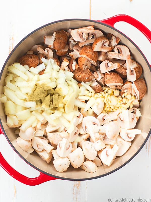 Sliced mushrooms, red and brown, in a cooking pot, with onions, garlic, and spice, ready to cook to become creamy mushroom pasta. 