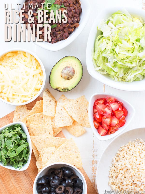 Fast and easy rice and beans dinner and toppings all in bowls. Toppings like cheese, avocado, cilantro, lettuce, tomatoes, and tortilla chips. Text overlay says "Ultimate Rice & Beans Dinner."