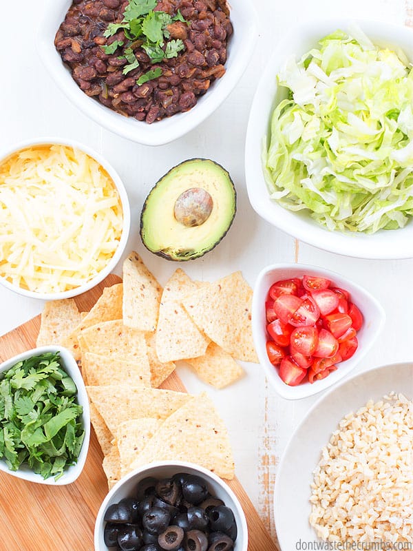Fast and easy rice and beans dinner and toppings all in bowls. Toppings like cheese, avocado, cilantro, lettuce, tomatoes, and tortilla chips.