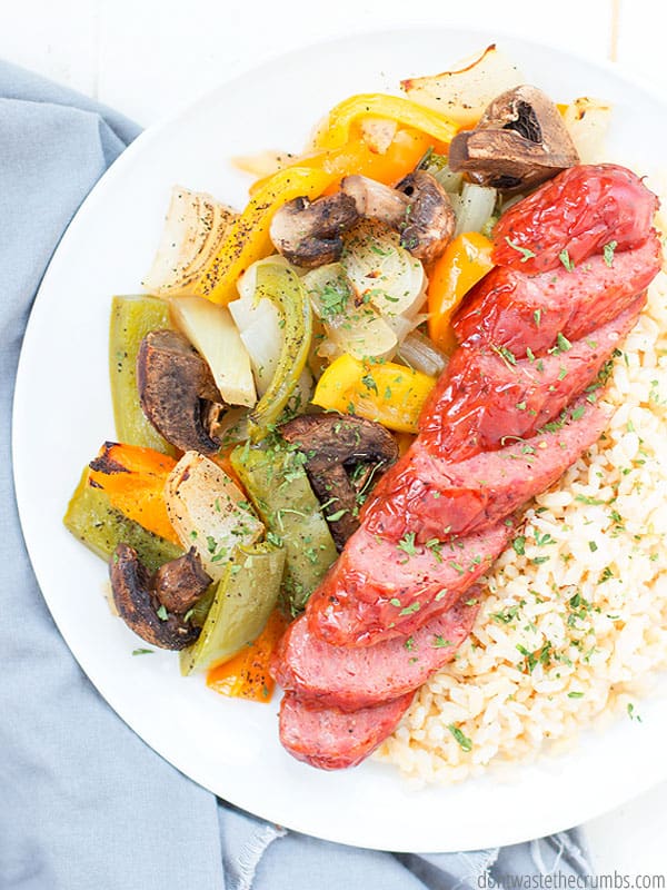 Roasted vegetables with sausages, sheet pan sausage and peppers with onions and mushrooms recipe served with rice. 