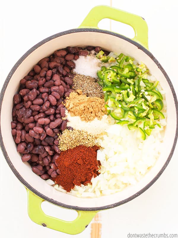 Cooked black beans recipe in a bowl with spices like chili powder, garlic, salt, oregano, cumin, and sage. The beans are covered with chopped jalepeno and onions. 