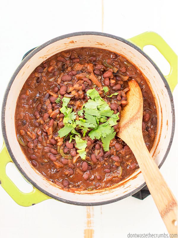 Black beans in a large bowl with a wooden spoon in it.