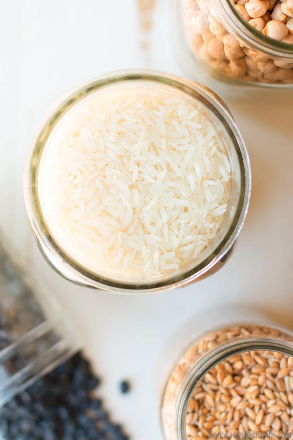 Jar of dried rice and wheat berries. A good way to save money on your grocery budget is to cook in bulk or batch cooking.