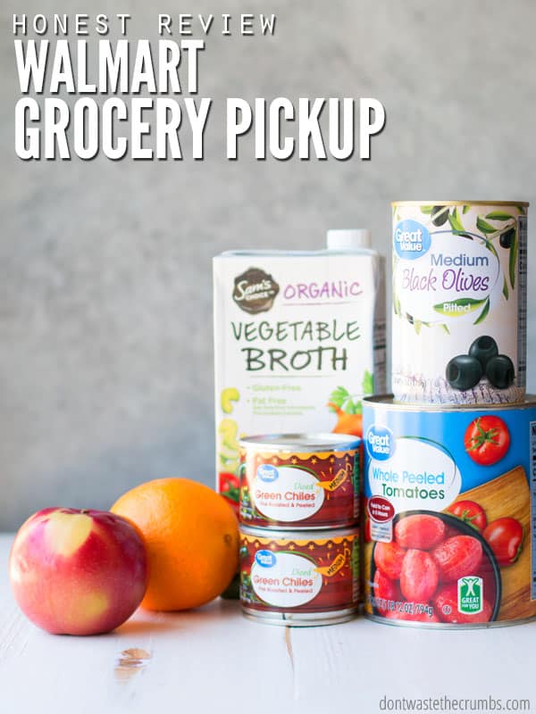 A selection of Walmart brand groceries sit on a counter, including a nectarine, an orange, two cans of green chilies, cans of olives and tomatoes, and a box of vegetable broth. Text overlay reads "Honest Review: Walmart Grocery Pickup."