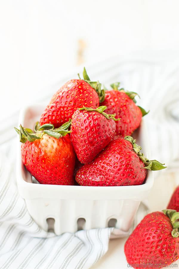 Plump, red strawberries sit in a pint container.