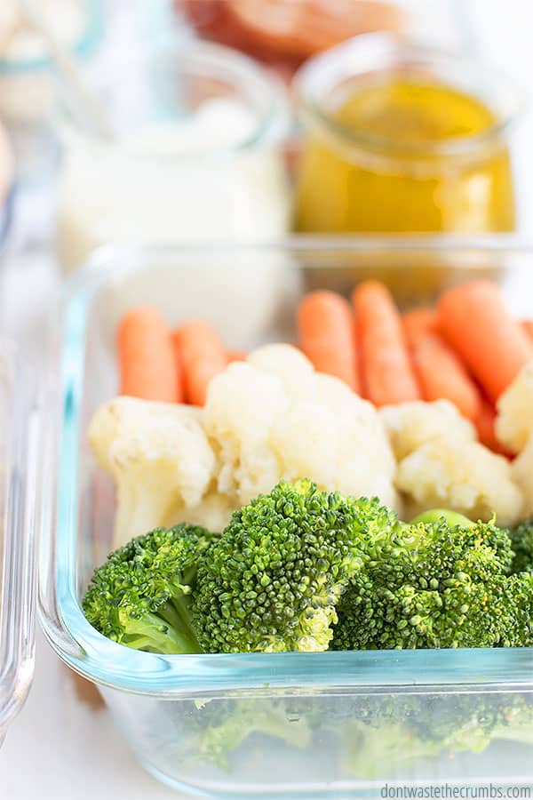 Glass container filled with carrots, cauliflower, and broccoli.