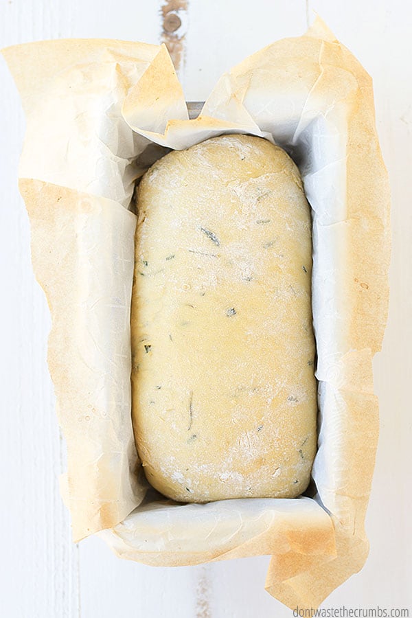 This rosemary olive oil bread is in a loafn pan with parchment paper and ready to go into the oven.