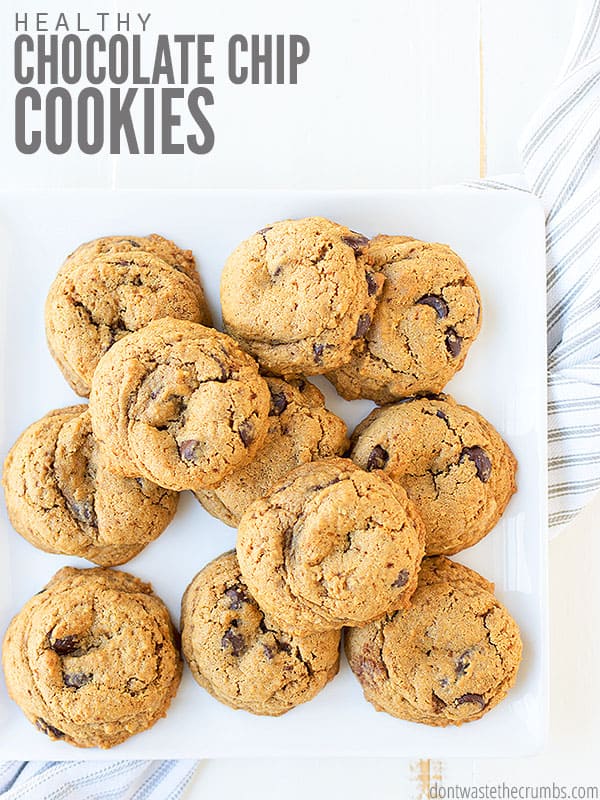 A pile of chocolate chip cookies on a square plate, with a dish towel underneath