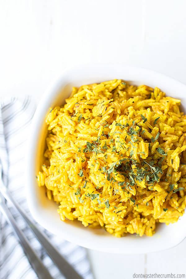 This yellow rice recipe is cooked and in a glass bowl on a table.