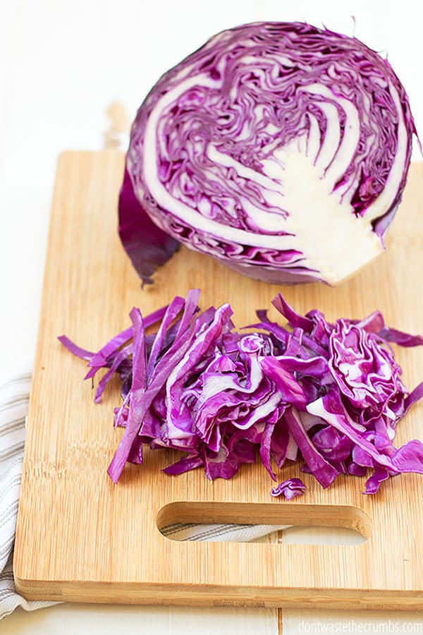 Freshly sliced purple cabbage on a wooden cutting board.