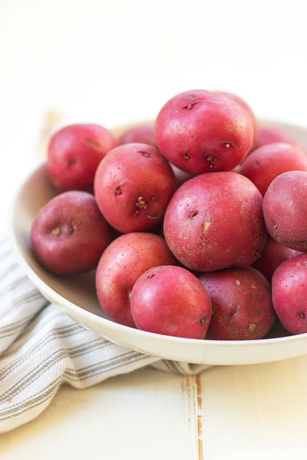 A bowl of fresh red skin potatoes sitting on top of a cloth.