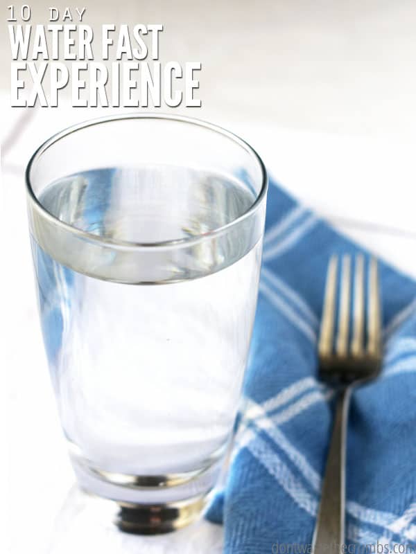 A clear glass of water on top of a blue kitchen towel. There is a fork on the towel beside the glass of water. Whether you choose to do a 7 day water fast, a 3 day fast, or somewhere in between, read about his experience, what you can drink on a water fast, and how to safely reintroduce food again. The text overlay reads "10 Day Water Fast Experience."  