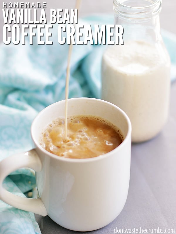 A mug of coffee, with a stream of homemade coffee creamer pouring into it. A bottle of creamer and a dish towel sit in the background.