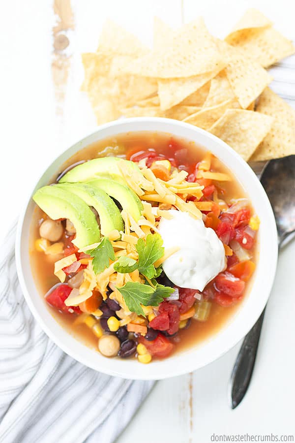 Bowl of tortilla soup with tortilla chips served on the side.