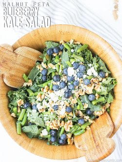 Easy recipe for kale salad made with massaged raw kale, blueberries, walnuts, feta, & balsamic vinaigrette. Serve with chicken or as is - great for summer!