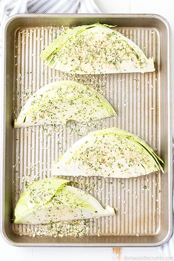 Four cabbage wedges on a rimmed baking sheet.