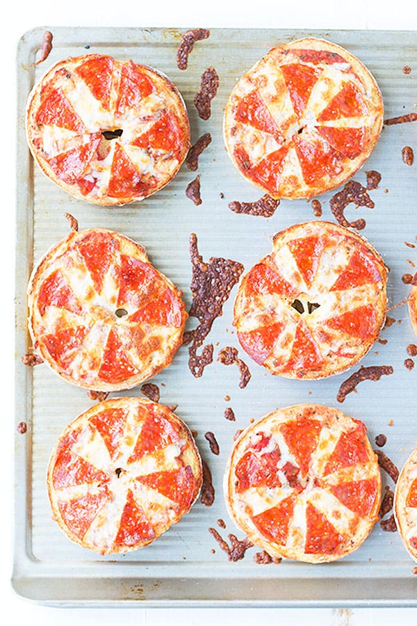 Pizza bagels that are cooked on a baking sheet.