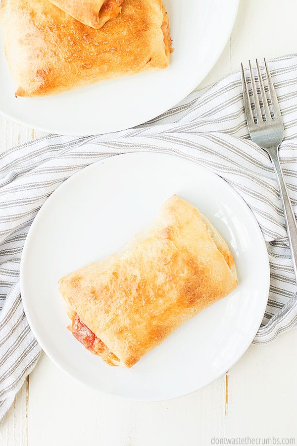 Pizza pocket on a white plate with a fork nearby.