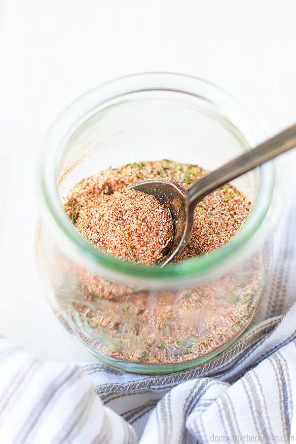 Homemade seasoning salt in a glass jar with a spoon mixing.