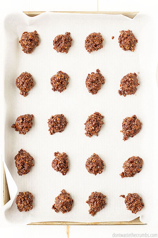 A birds eye view of 20 no bake cookies on a piece of parchment paper on top of a cookie tray.