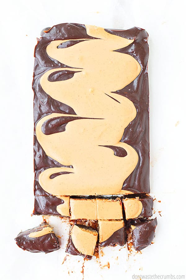 A rectangle of fudge with peanut butter swirled into the top of it. The background is white and the fudge has eight square pieces portioned out from the bottom. 