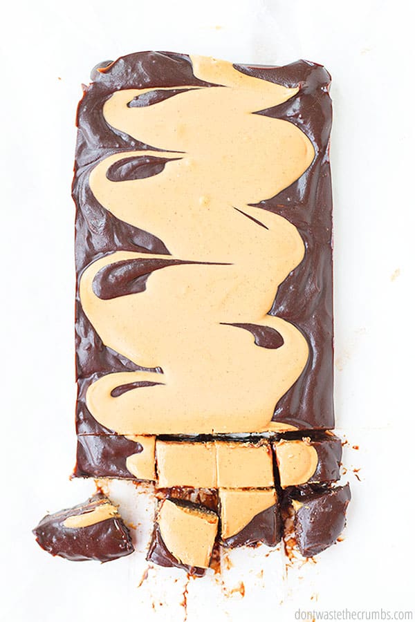 A rectangle of fudge with peanut butter swirled into the top of it. The background is white and the fudge has eight square pieces portioned out from the bottom.