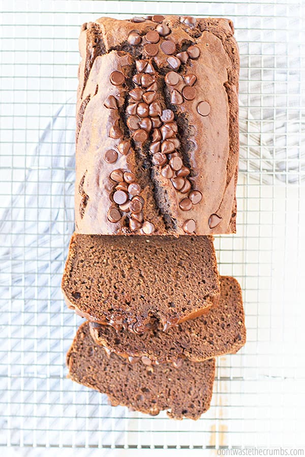 Homemade chocolate banana bread on a cooling rack. Half of the loaf is in slices.