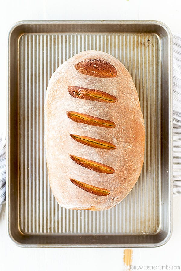 A golden brown loaf of bread. With a wonderfully crisp crust its on a baking sheet. 
