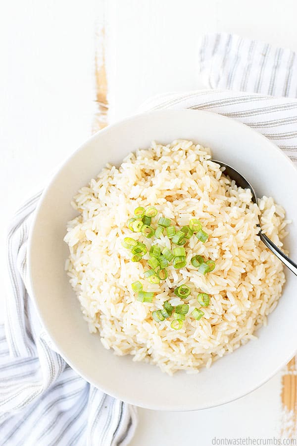 Parboiled rice in a white bowl with a spoon