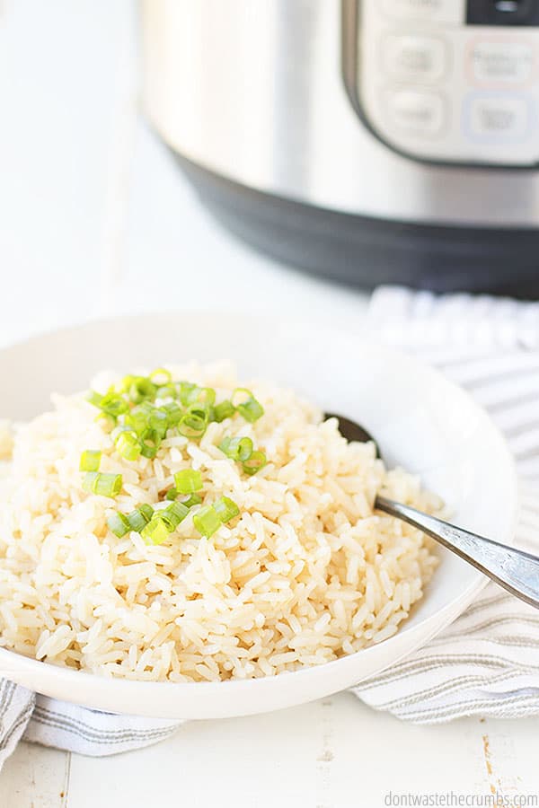 Parboiled rice in a white bowl with a spoon and an Instant Pot in the background