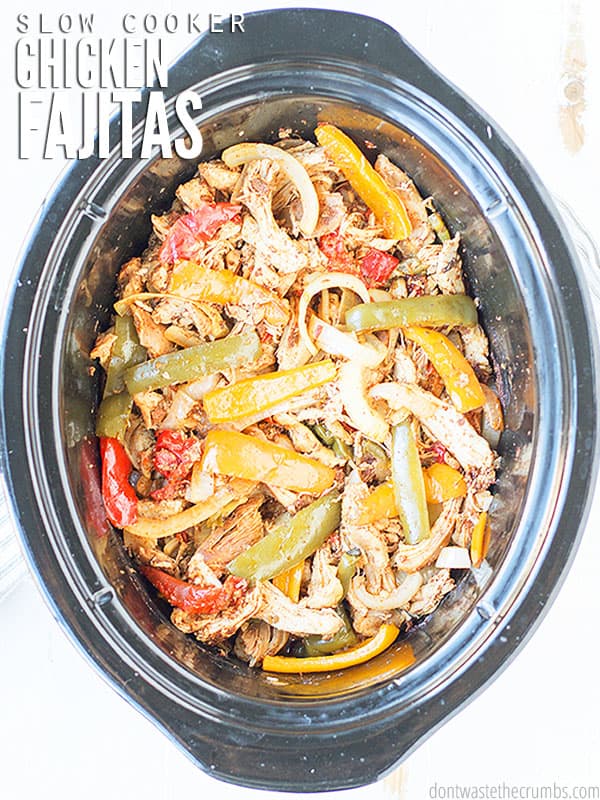 Cooked chicken mixed with peppers, onions, and seasonings inside of an slow cooker. The text over lay says, "Slow Cooker Chicken Fajitas".