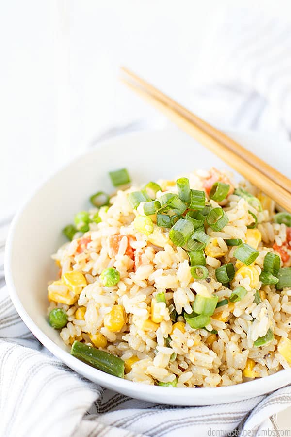 A white bowl of fried rice, corn, and green onions. You can eat it how you please, but I love to use some wooden chopsticks