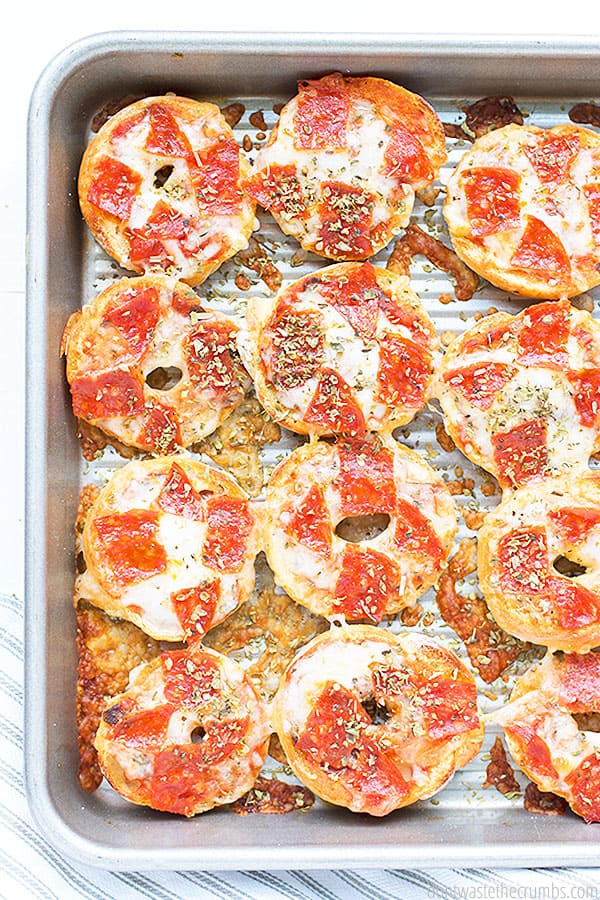 Baking sheet full of mini pizza bagels.