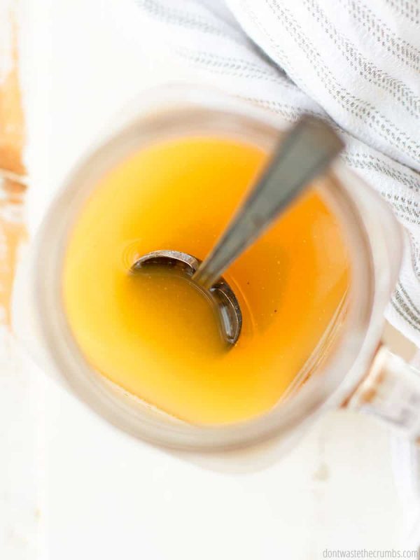 A glass of apple cider vingear with a spoon in it is viewed from above.