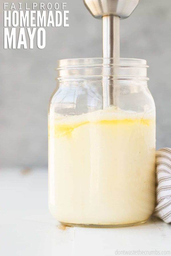 Large mason jar with homemade mayonnaise with an immersion blender mixing. Text overlay reads Failproof Homemade Mayo.
