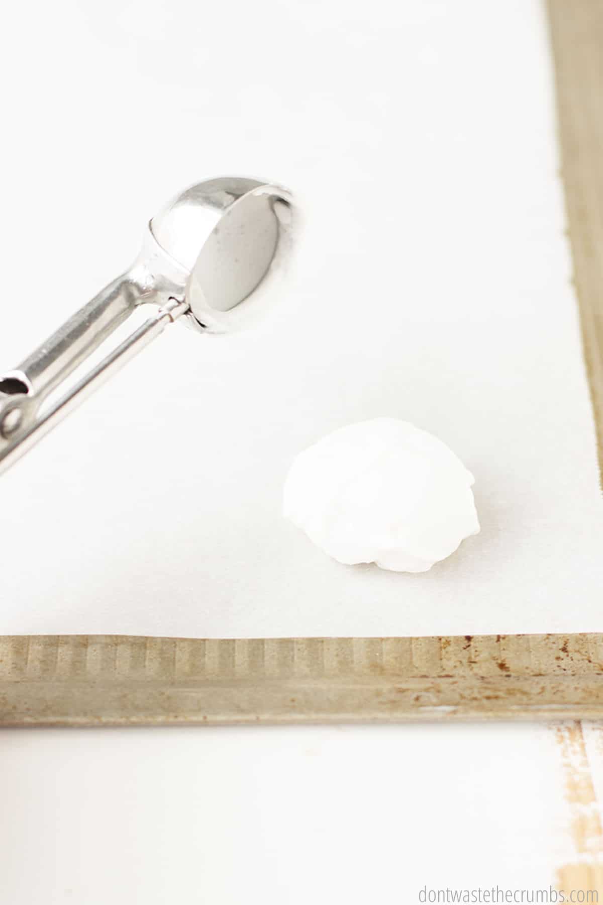 A perfect scoop of yogurt being placed on a parchment lined sheet pan. 