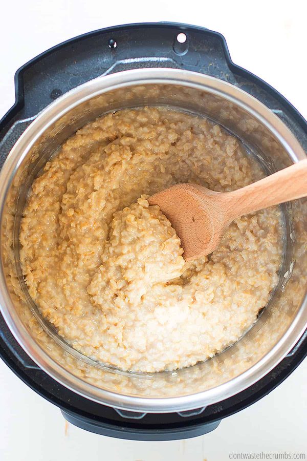 Instant Pot with oatmeal. Wooden spoon is stirring the oatmeal.