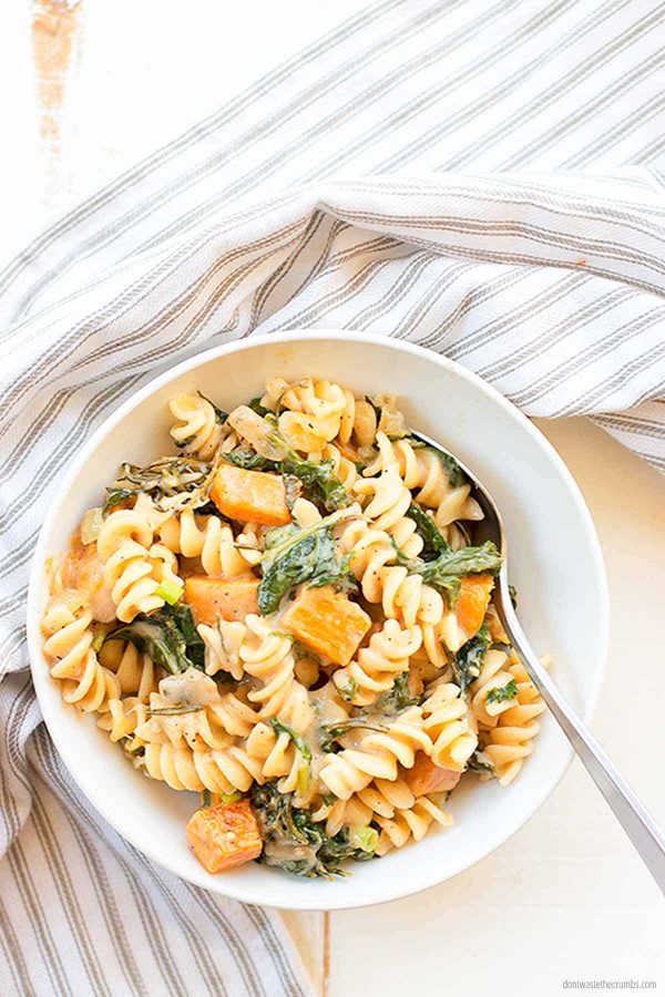 This Savory bacon, onion and greens pasta skillet id laid out on a plate, ready to eat. This fits perfectly in the weekly plan for $50.