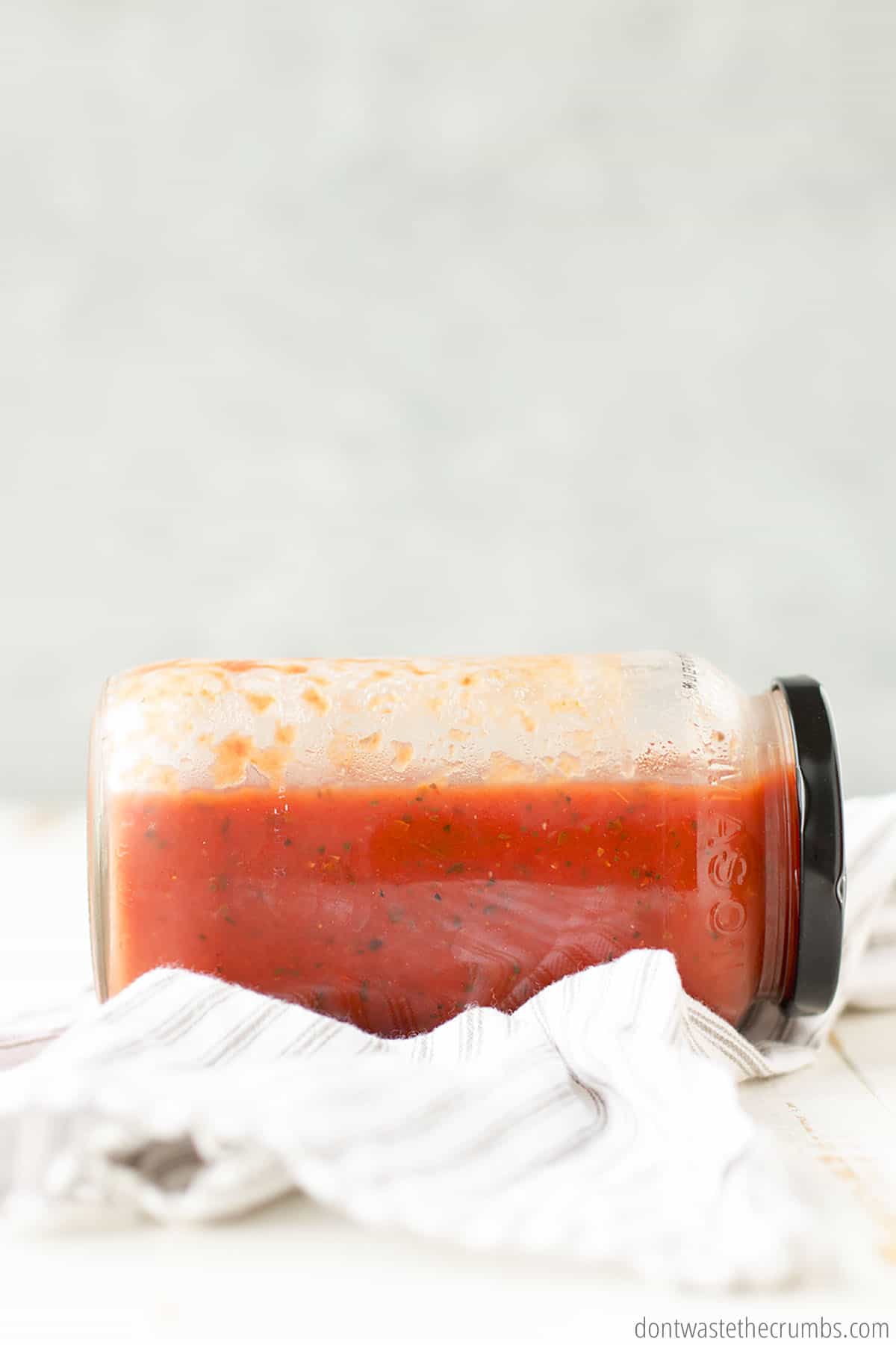 This mason jar filled with hearty spaghetti sauce is stored on its side with plenty of open space along the upper length for expansion.