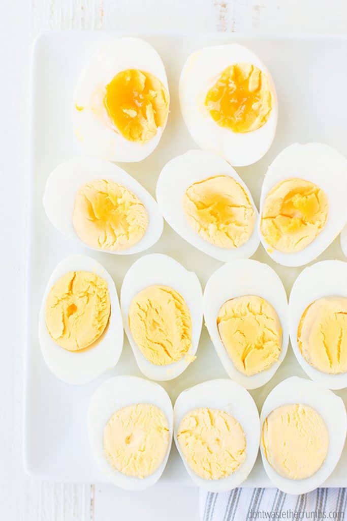 Boiled eggs, ranging from runny, soft-boiled eggs, to fully hard-boiled eggs, are displayed on a white tray.